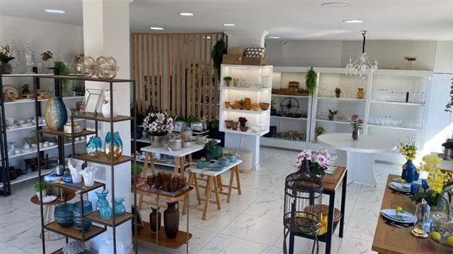 Interior da loja HOME em Camapuã, com poltronas e objetos de decoração dispostos com luz natural.
